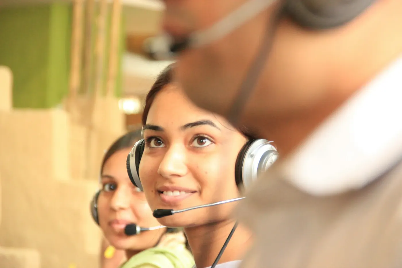 Two support team members wearing headsets in a bright office